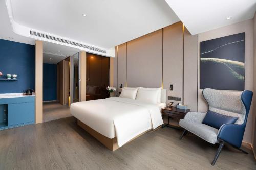a bedroom with a large white bed and a chair at Atour Hotel Hengyang South Mountain Hengshan Scenic Area in Nanyue