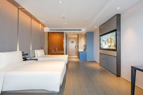 two beds in a hotel room with a flat screen tv at Atour Hotel Kunshan Baoyu Plaza North Changjiang Road in Kunshan