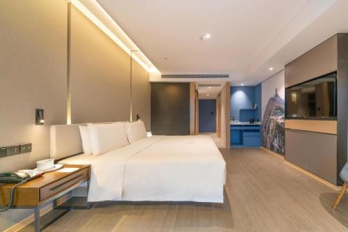 1 dormitorio con 1 cama blanca grande y TV en Atour Hotel Chongqing Yongchuan High-Speed Xinglong Lake, en Yongchuan