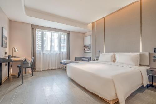 ein Schlafzimmer mit einem großen weißen Bett und einem Schreibtisch in der Unterkunft Atour Hotel Taizhou Maoye World in Taizhou