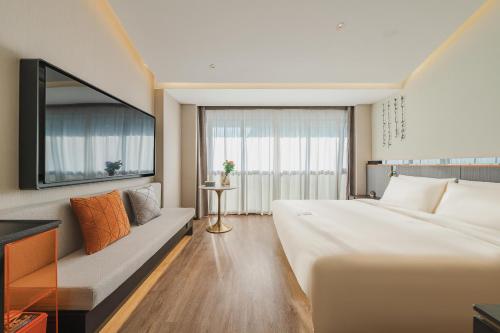 a hotel room with a large bed and a couch at Atour S Hotel Wuxi Nanchang Street in Wuxi