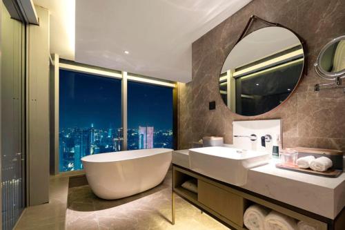 a bathroom with a tub and a sink and a mirror at Atour Hotel Wuhan Hankou Financial Center in Wuhan