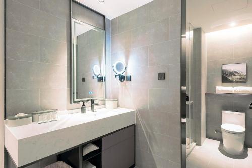 a bathroom with a sink and a toilet and a mirror at Atour Hotel Wuhan Optics Valley Square Yangjia Bay in Wuhan
