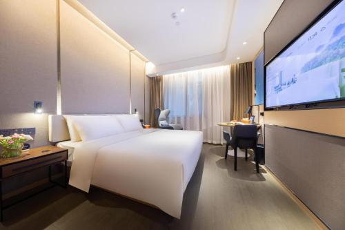 a hotel room with a white bed and a flat screen tv at Atour Hotel Nanjing Drum Town Qingliang Gate in Nanjing
