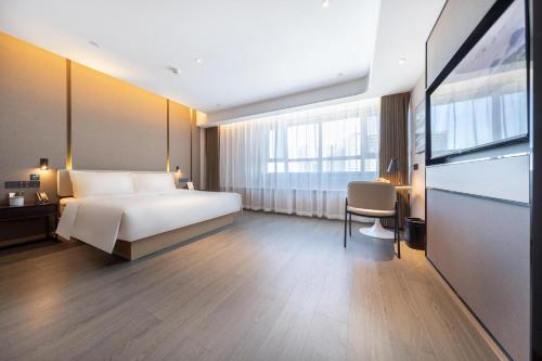 a bedroom with a bed and a desk and a tv at Atour Hotel Sanhe Yanjiao Development District in Sanhe