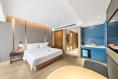 a bedroom with a white bed and a blue wall at Atour Hotel Ya an Era Street in Ya'an