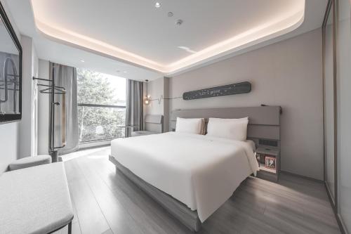 a bedroom with a white bed and a large window at Atour Light Hotel Nantong Drum Plaza South Street in Nantong