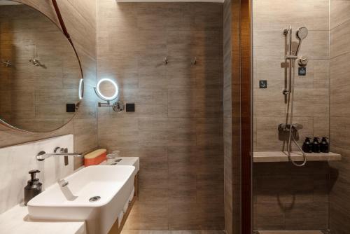 a bathroom with a shower and a sink and a mirror at Atour Hotel Lanzhou Xiguan Zhangye Road Pedestrian Street in Lanzhou