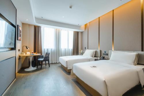 a hotel room with two beds and a desk at Atour Hotel Basketball Nanchang West Station in Nanchang