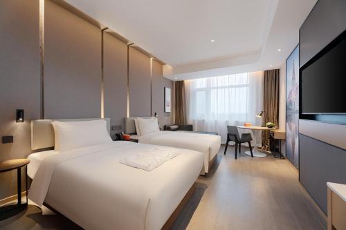 a hotel room with two beds and a flat screen tv at Atour Hotel Qingdao Jiaodong International Airport in Jiaoxian