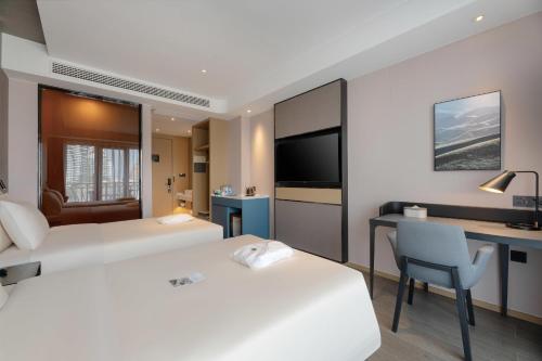 a hotel room with two beds and a desk and a tv at Atour Hotel Xishuangbanna Jinghong Gaozhuang Starlight Night Market in Jinghong