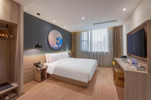 Cette chambre comprend un lit blanc et une télévision. dans l'établissement Atour Light Hotel Nantong West Youth Road, à Nantong