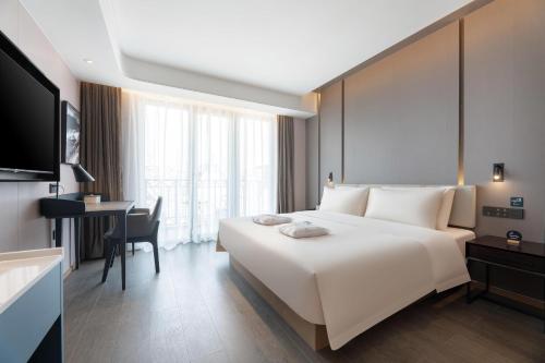 a hotel room with a large white bed and a desk at Atour Hotel Xishuangbanna Jinghong Gaozhuang Starlight Night Market in Jinghong