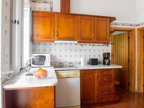 una cocina con armarios de madera y un bol de fruta en la barra en Idyllic Farmhouse in Montemor o Novo with Pool, en Montemor-o-Novo