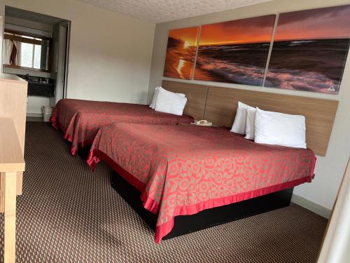 a hotel room with two beds and a painting on the wall at Days Inn & Suites by Wyndham Dayton North in Dayton