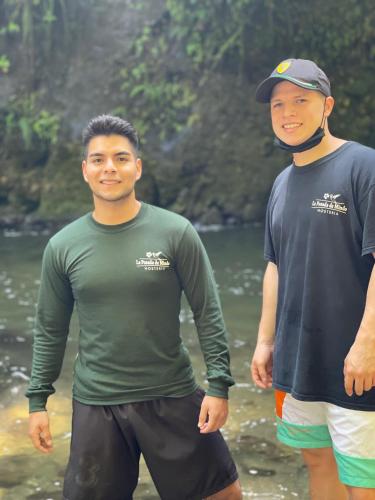 two men standing in the water on a beach at La Posada de Mindo in Mindo