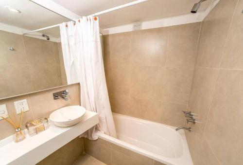 y baño con bañera, lavamanos y ducha. en Pacífico Apartamentos Ribera en Ushuaia