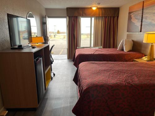 a hotel room with two beds and a flat screen tv at Days Inn & Suites by Wyndham Dayton North in Dayton