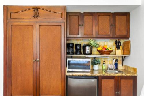 a kitchen with wooden cabinets and a counter top at Islander Ocean Resort Condo # 166 in Kapaa