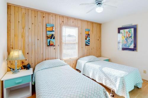 two beds in a bedroom with wood paneling at Charmed Life RO22 in Rodanthe