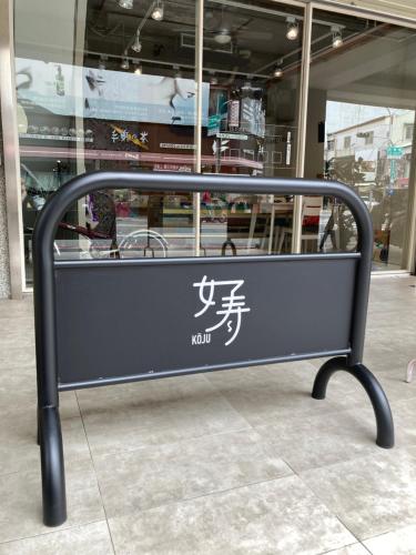 un banco con un cartel delante de una tienda en 台南包棟 好寿民宿 Koju貸切一軒家, en Tainan