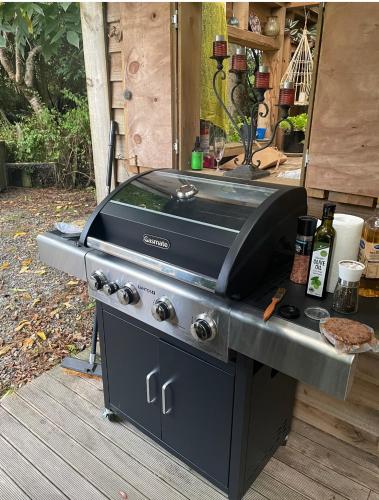 a grill sitting on top of a wooden deck at The kauri Tree Pod - Off Grid Experience in Levin
