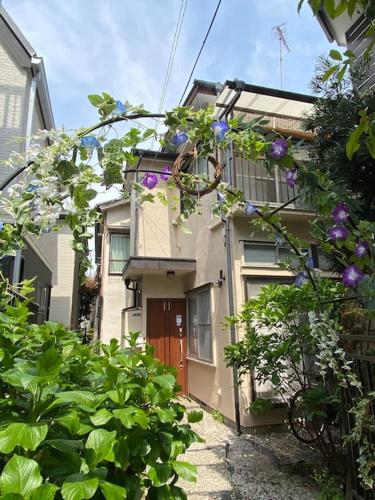 a house with purple flowers in front of it at 2025年グッドレビュー賞受賞 広々一軒家 最大9名 空港直通 山手線すぐ80m2庭付き大福ハウス in Tokyo