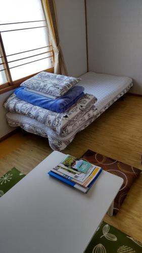 a room with a bed and a book on a table at Guest House Yamada in Date