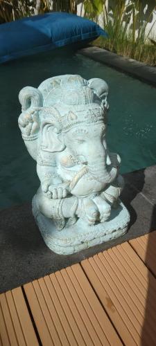 a stone statue sitting next to a swimming pool at The Seaglass Villas Bingin in Uluwatu