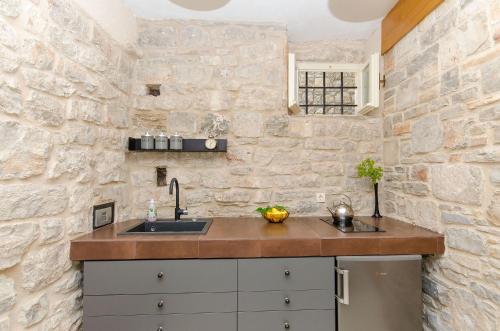 a kitchen with a sink and a stone wall at Apartment Pavlimir in Stomorska