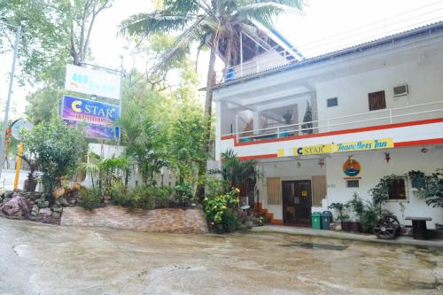 a white building with a sign in front of it at C Star Travellers Inn in Oslob