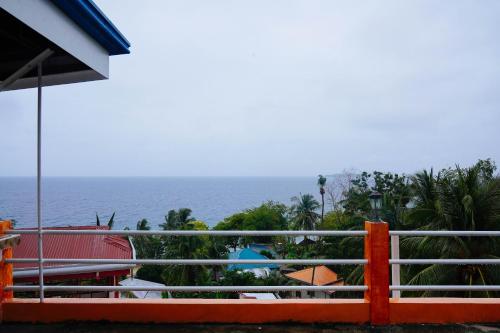 a view of the ocean from a house with an orange fence at C Star Travellers Inn in Oslob