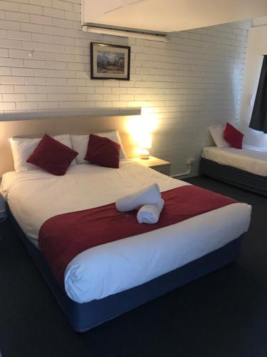 a bedroom with a large bed with red and white pillows at Kaputar Motel in Narrabri