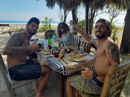 a group of three men sitting at a table eating food at Popoyo Surfcamp in Popoyo