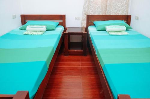 two beds in a room with blue sheets at C Star Travellers Inn in Oslob