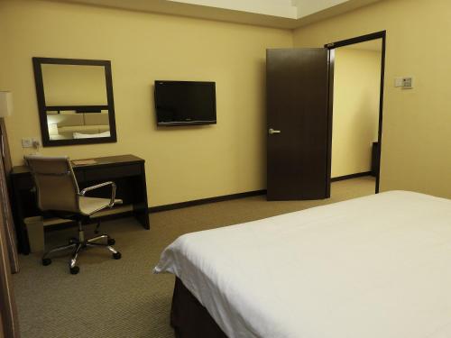 a hotel room with a bed and a desk and a mirror at Ixora Hotel Penang in Perai
