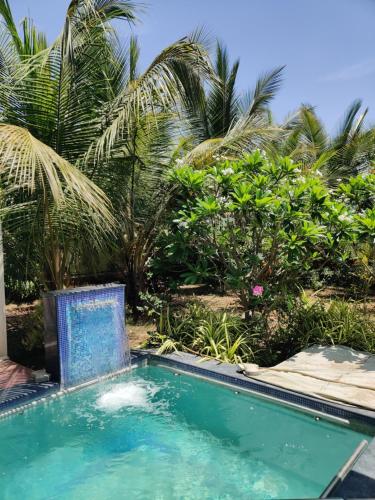 een zwembad voor enkele palmbomen bij Narayani Resort - Serene resort with private swimming pool in Tiruvannamalai