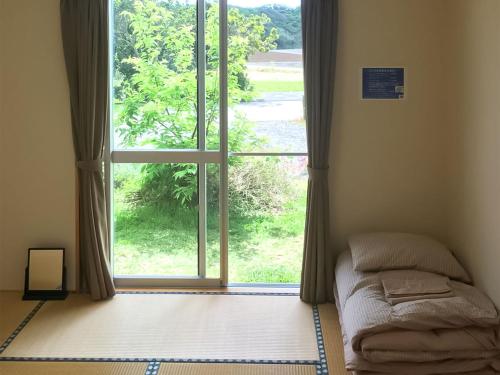 um quarto com uma cama em frente a uma janela em Pension Ntsunaka em Ilhas Miyako