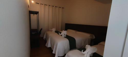 a room with four beds with white comforters at Pensión Mar in Portomarin