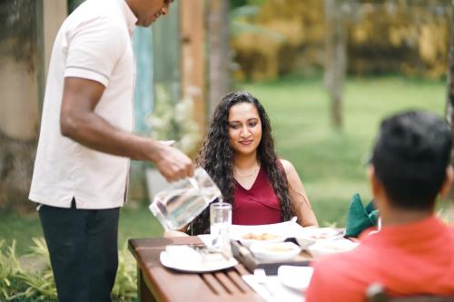 a man pouring wine at a table with a woman at Gedara Villa in Kalutara