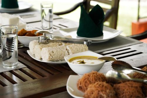 a table with plates and bowls of food on it at Gedara Villa in Kalutara