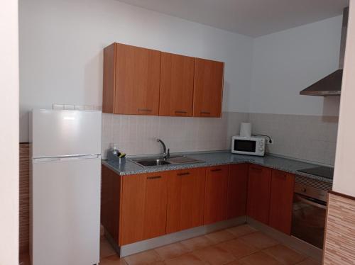 uma cozinha com armários de madeira e um frigorífico branco em Casa ERIZO em Caleta de Sebo