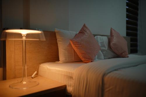 a bed with pillows and a lamp on a table at Chandra Inn in Kollam