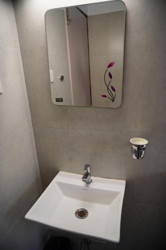 uma casa de banho com um lavatório branco e um espelho. em Chandra Inn em Coulão