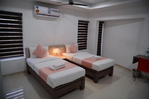 a room with two beds and a couch and windows at Chandra Inn in Kollam