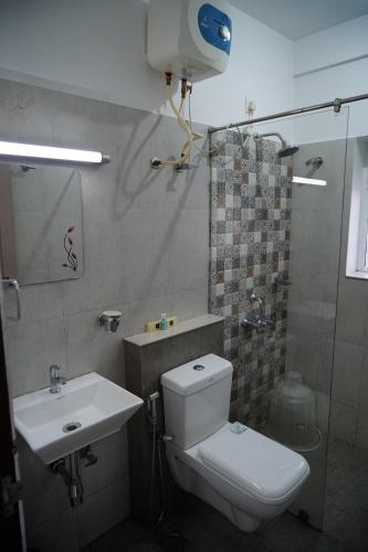 a bathroom with a toilet and a sink and a shower at Chandra Inn in Kollam