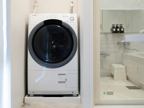 a washing machine in a bathroom next to a bath tub at Artist Hotel - BnA STUDIO Akihabara in Tokyo