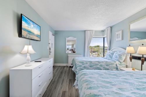a bedroom with two beds and a tv on the wall at Hosteeva 1BR Oceanfront Condo in Atlantica Resort near Boardwalk in Myrtle Beach