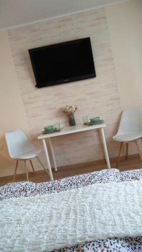 a living room with a tv on a wall with two chairs at River Side Apartman in Kalocsa