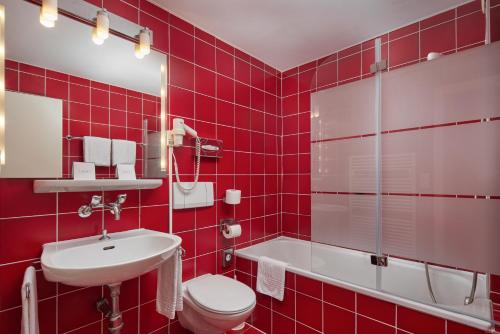 uma casa de banho com azulejos vermelhos, um WC e um lavatório. em Bon Port em Montreux